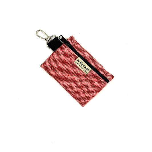 Red woven pouch with black strap and gold tag on a white background
