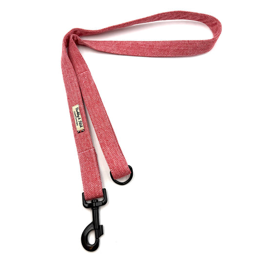 Red dog leash with a black clip on a white background