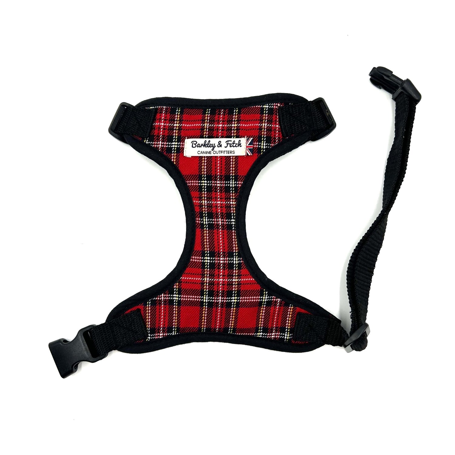 A red and black tartan fabric dog harness with adjustable straps and a metal D-ring, displayed on a white background.