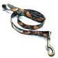 A dog lead with a floral pattern in black, green, and pink colors, featuring a metal trigger hook and a D-ring on the handle.