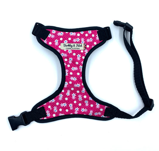 Adjustable hot pink floral print dog harness with black straps and a side release buckle, on a white background.