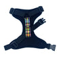 Black dog harness with a colorful plaid patch on a white background