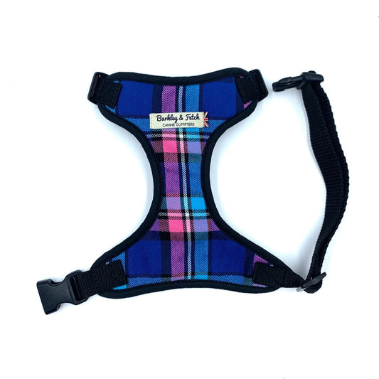 A checkered pink and blue fabric dog harness with a black side release buckle and webbing, and a branded label at the neck.
