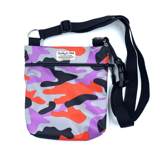 A lavender and red camo dog walk and treat bag with an adjustable long shoulder strap, a zip fastening, and a special pocket for poo bags.