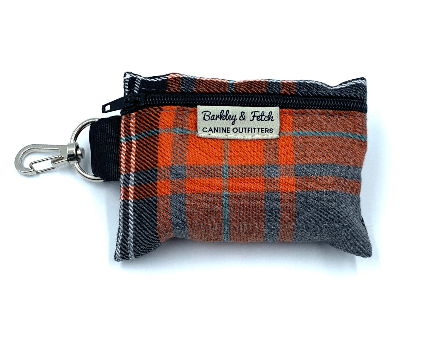A tartan patterned poo bag holder with orange, grey, and black colors, featuring a clip and a label that reads 'Barkley & Fetch'.