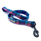 A pink and blue check dog lead with a heavy duty metal trigger hook and a D-ring on the handle.