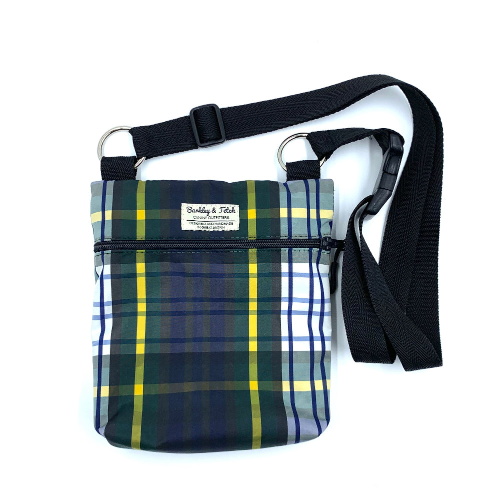 A plaid patterned dog walking and treat bag with a black shoulder strap, displayed against a white background.